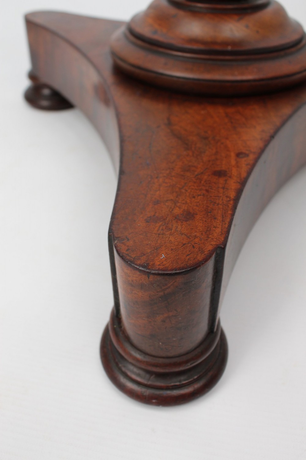 A circular mahogany wine table from the William IV period featuring a turned central column on a triform base with flattened bun feet. View VII