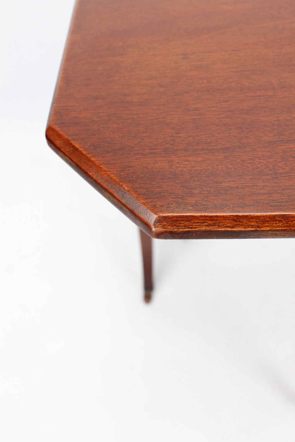 A compact Edwardian mahogany Sutherland table with folded side leaves, slatted end supports, and legs fitted with brass castors. View V
