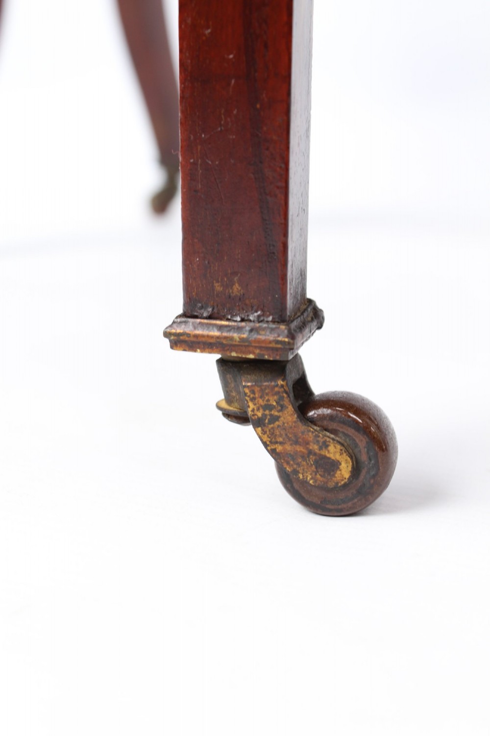 A compact Edwardian mahogany Sutherland table with folded side leaves, slatted end supports, and legs fitted with brass castors. View VII