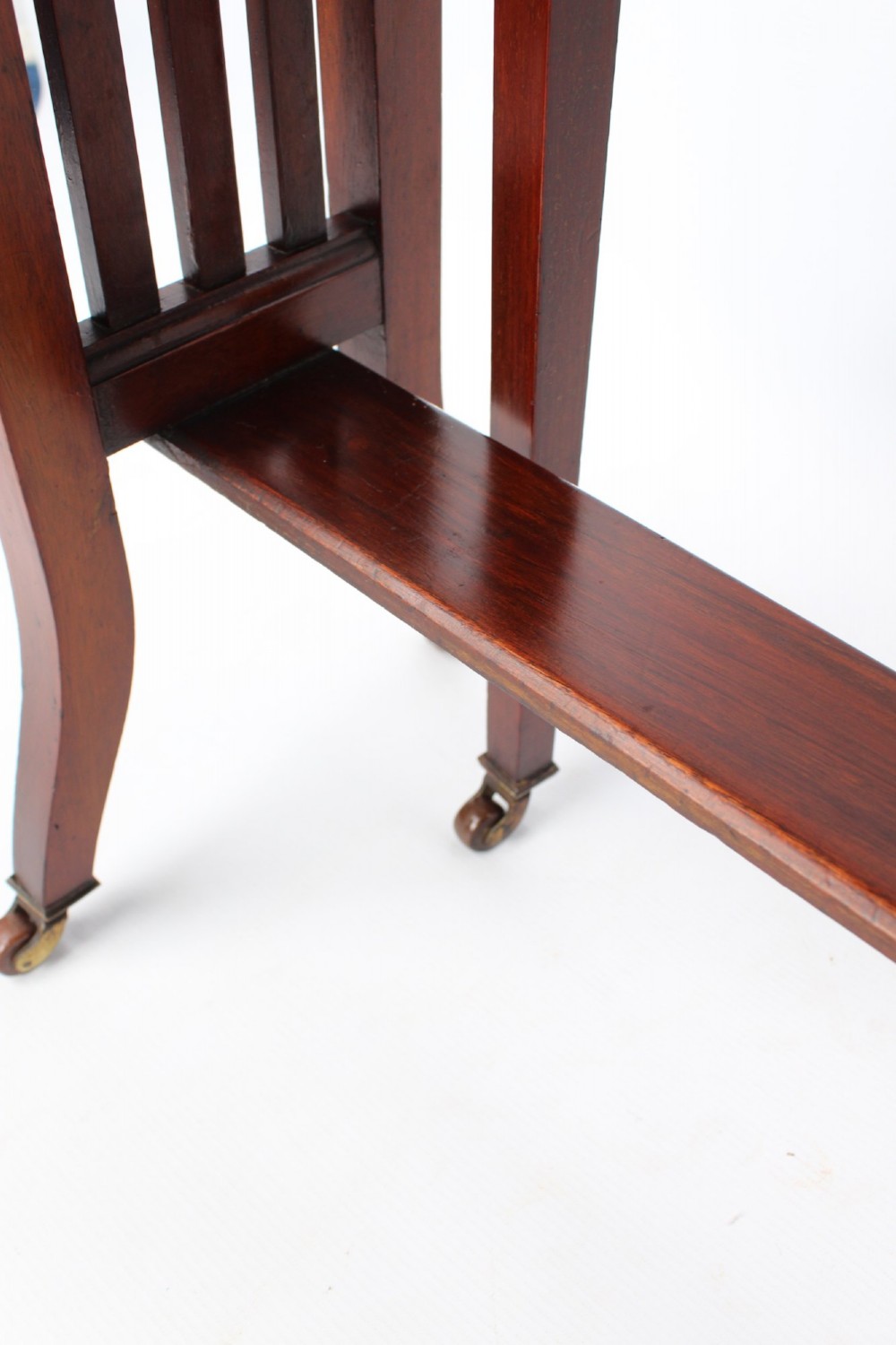 A compact Edwardian mahogany Sutherland table with folded side leaves, slatted end supports, and legs fitted with brass castors. View VIII