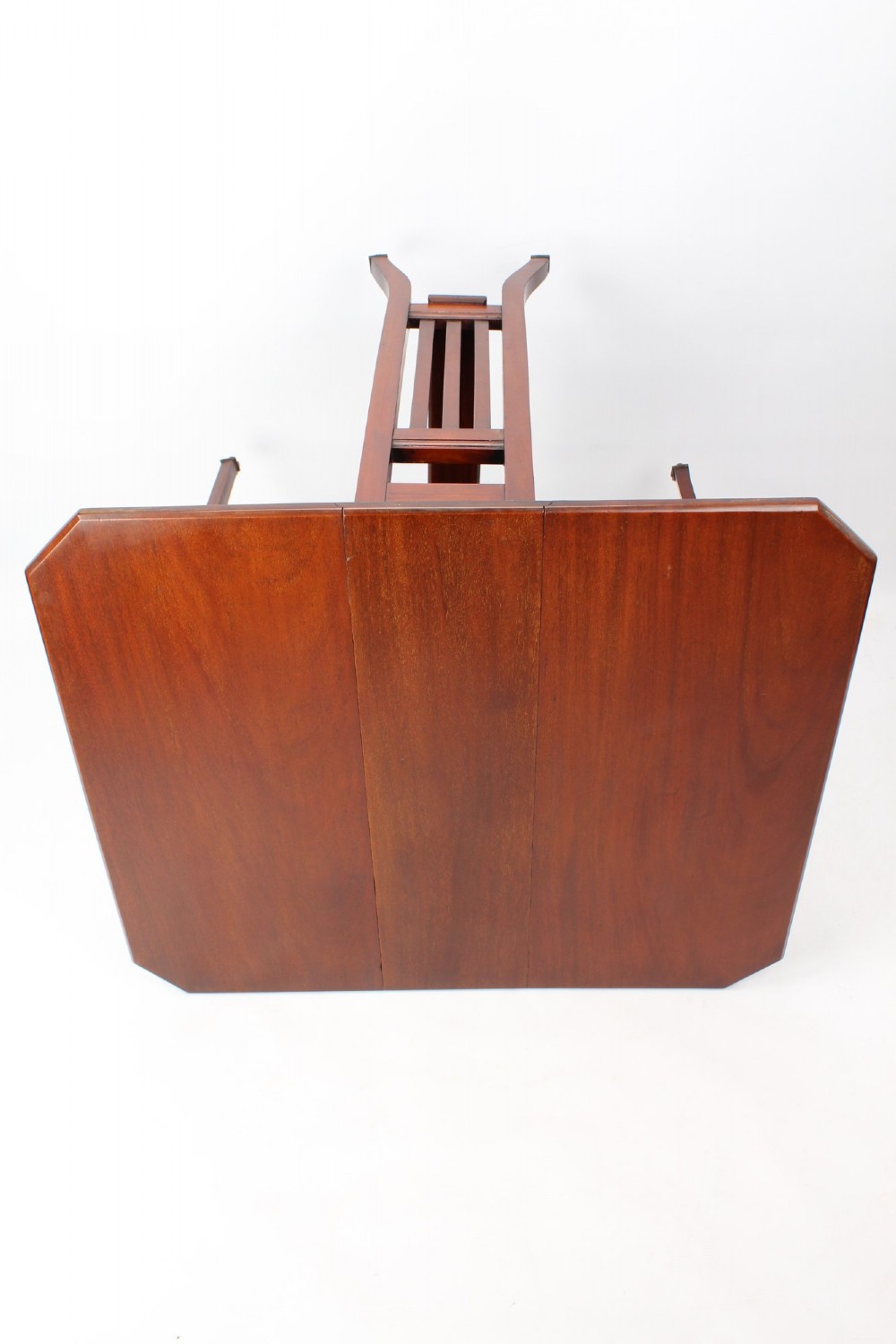 A compact Edwardian mahogany Sutherland table with folded side leaves, slatted end supports, and legs fitted with brass castors. View XI