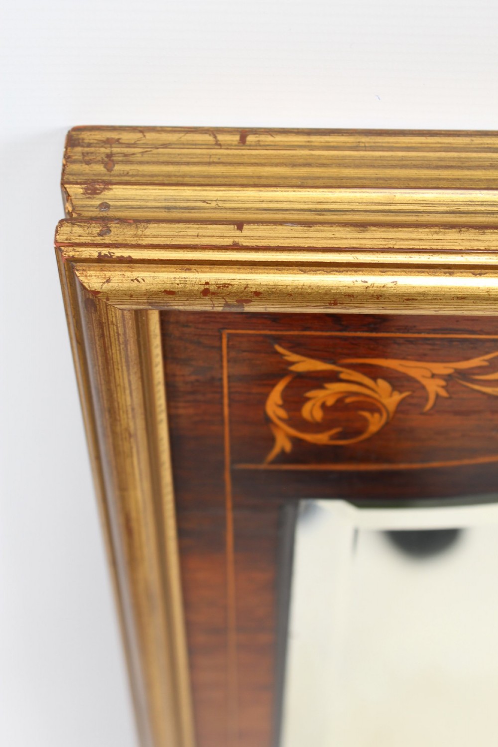 A rectangular rosewood wall mirror featuring gilt outer moulding, floral corner marquetry inlays, and an arched bevelled glass plate. View IV