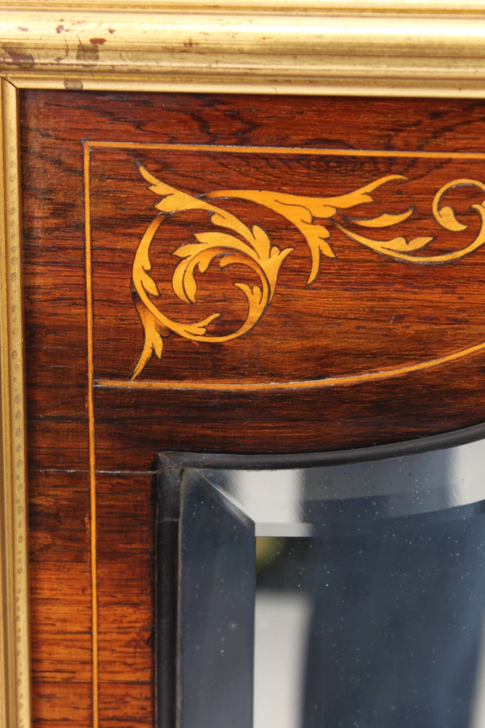 A rectangular rosewood wall mirror featuring gilt outer moulding, floral corner marquetry inlays, and an arched bevelled glass plate. View VI