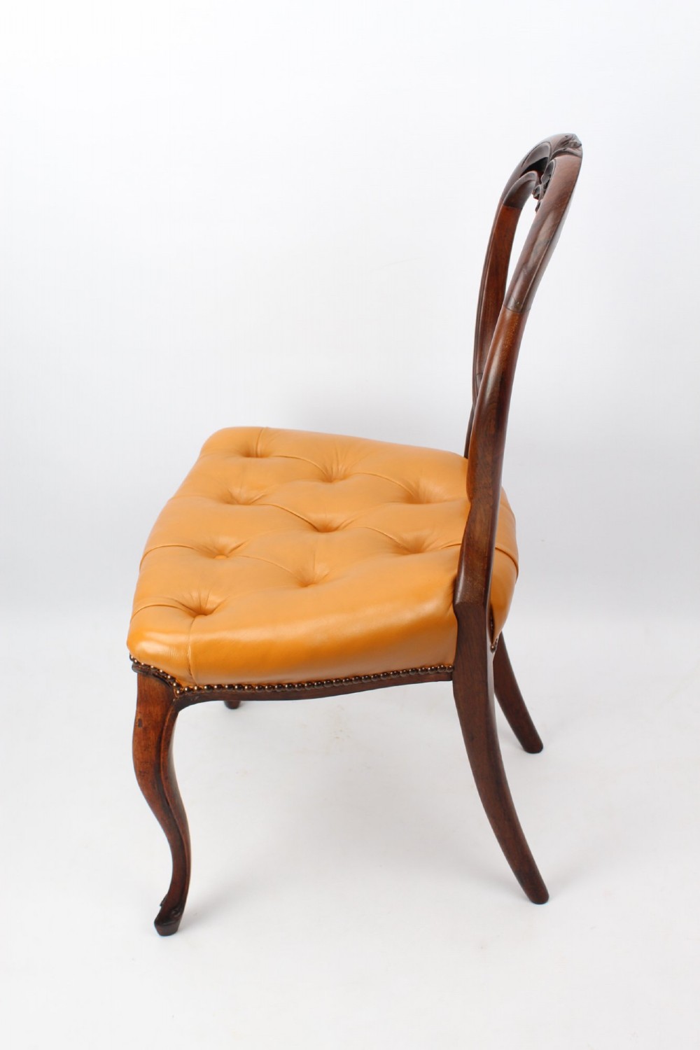 A pair of Victorian rosewood balloon back side chairs featuring button-tufted tan leather upholstery and cabriole front legs. View IV