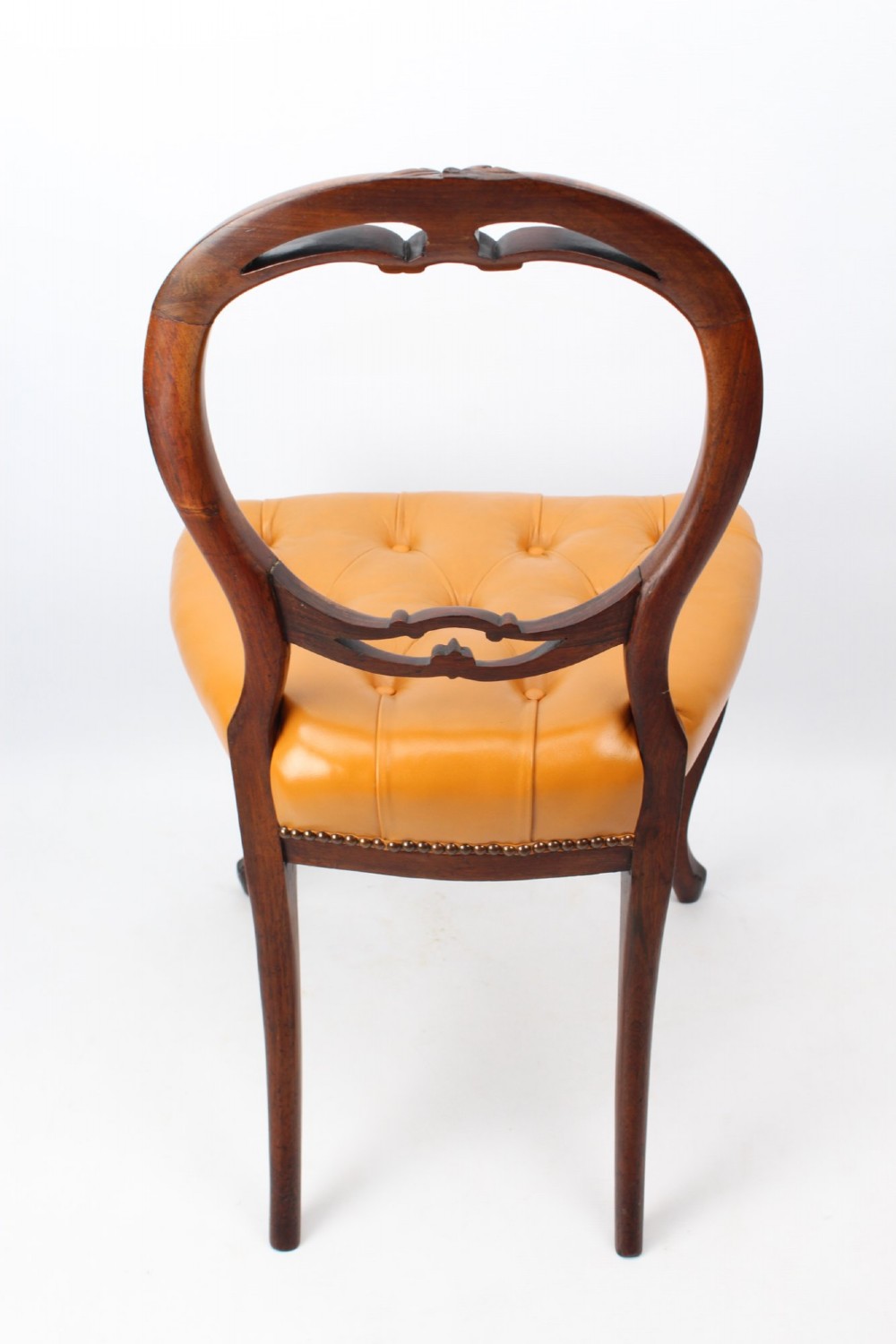 A pair of Victorian rosewood balloon back side chairs featuring button-tufted tan leather upholstery and cabriole front legs. View V