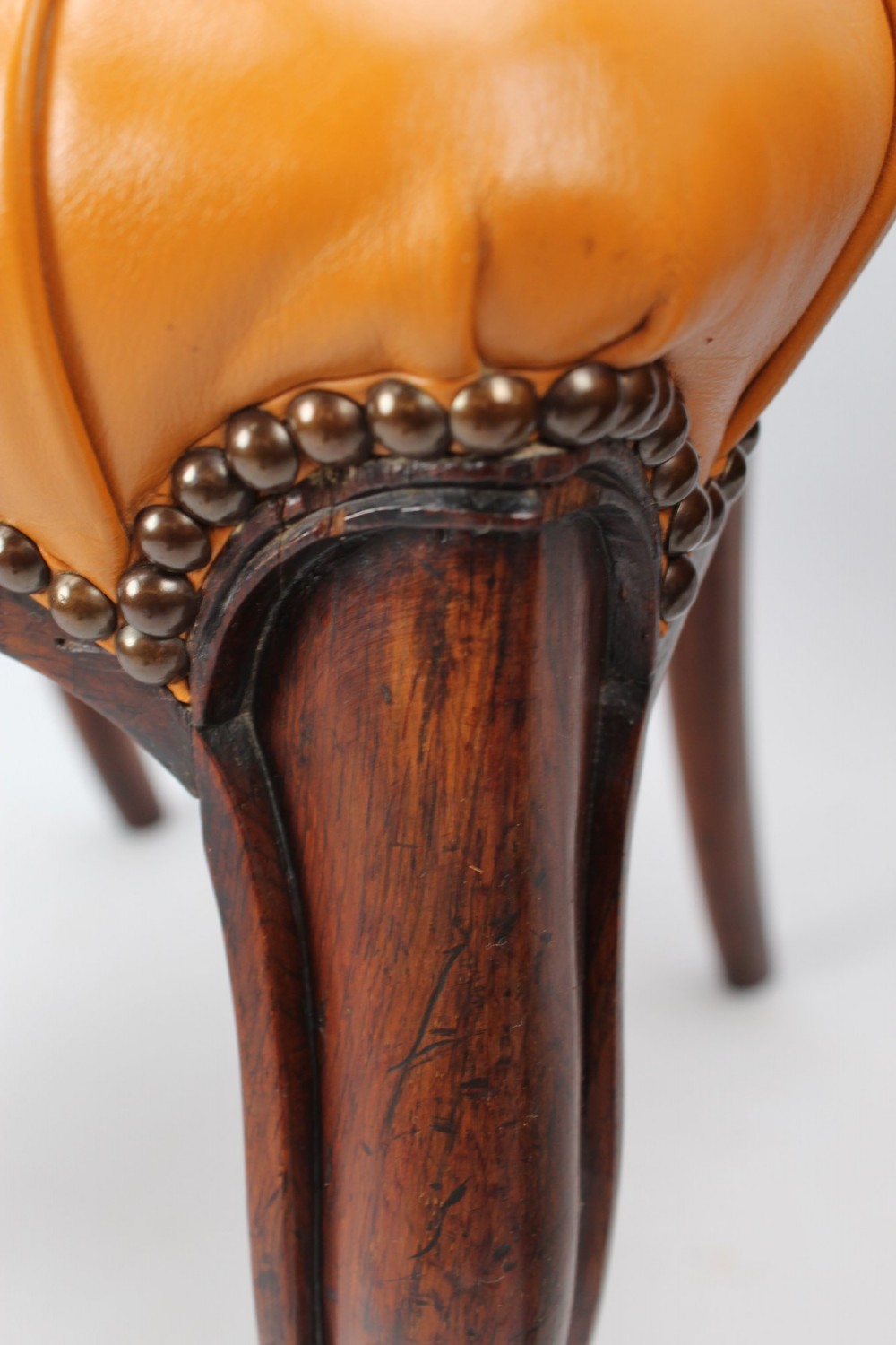 A pair of Victorian rosewood balloon back side chairs featuring button-tufted tan leather upholstery and cabriole front legs. View X