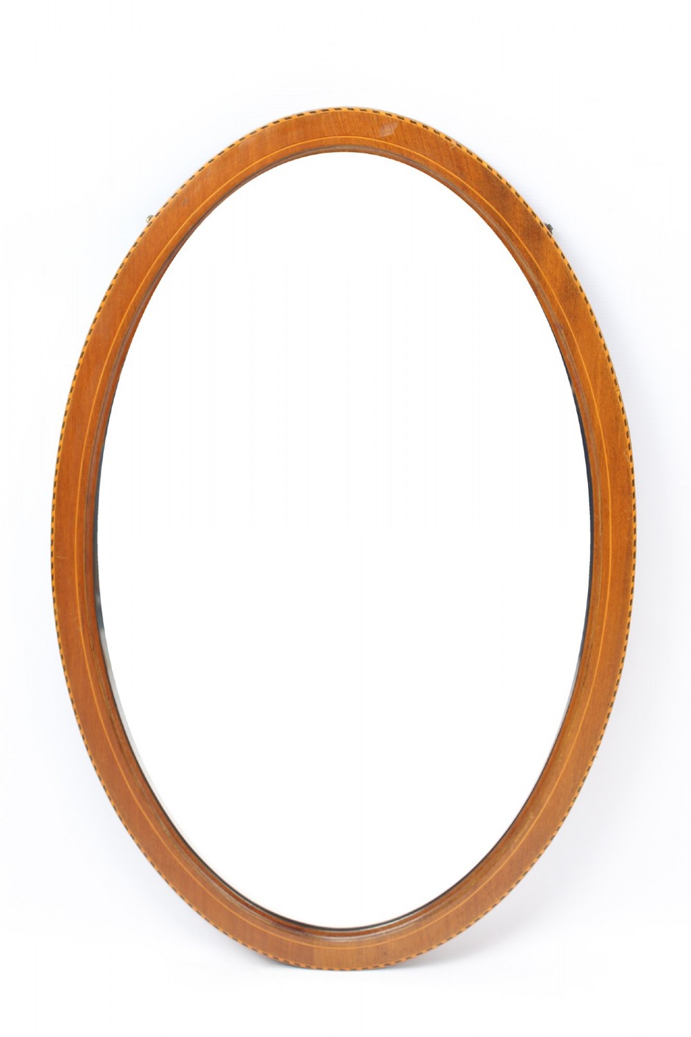 An oval wall mirror framed in warm mahogany timber with geometric chequered inlay along the outer border.