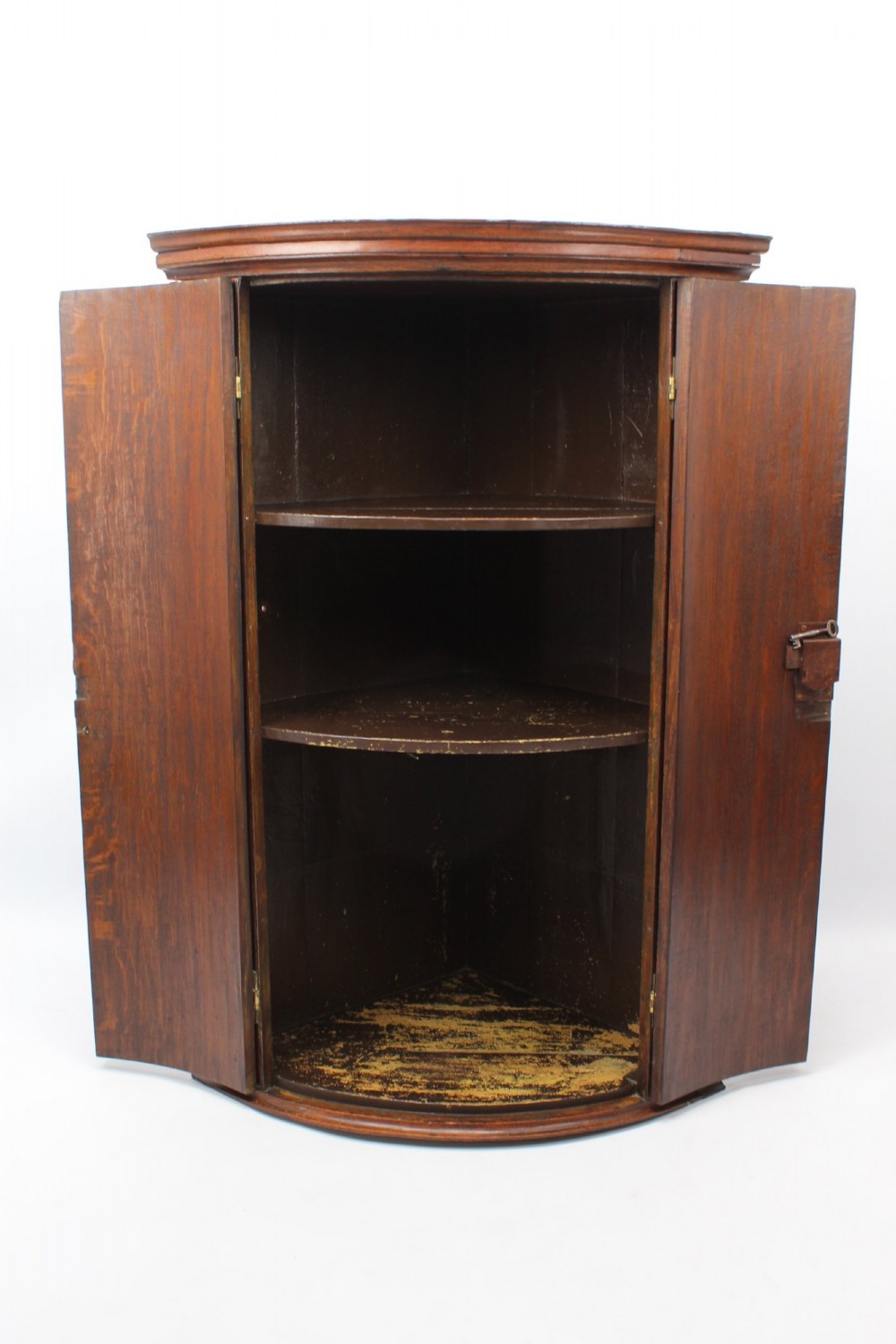 A Georgian oak bow-front corner cupboard with twin doors, exposed brass H-hinges, crossbanded veneer borders, and central brass escutcheons. View III