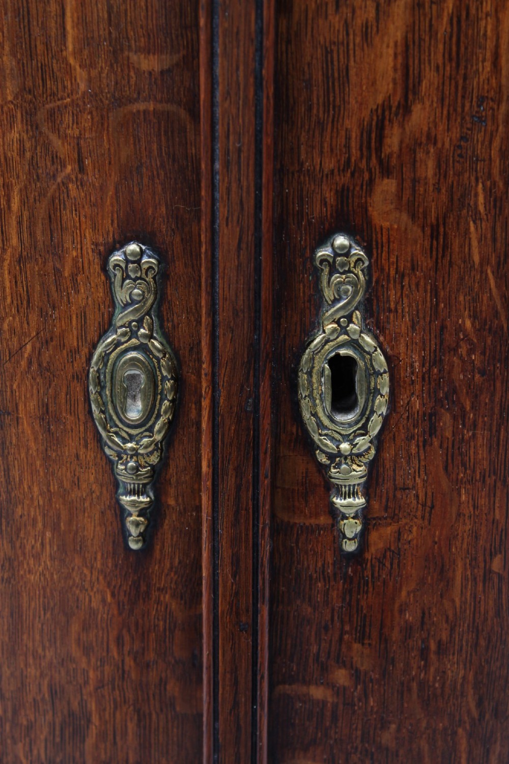 A Georgian oak bow-front corner cupboard with twin doors, exposed brass H-hinges, crossbanded veneer borders, and central brass escutcheons. View VI