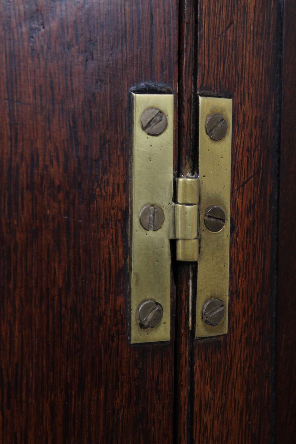 A Georgian oak bow-front corner cupboard with twin doors, exposed brass H-hinges, crossbanded veneer borders, and central brass escutcheons. View VII