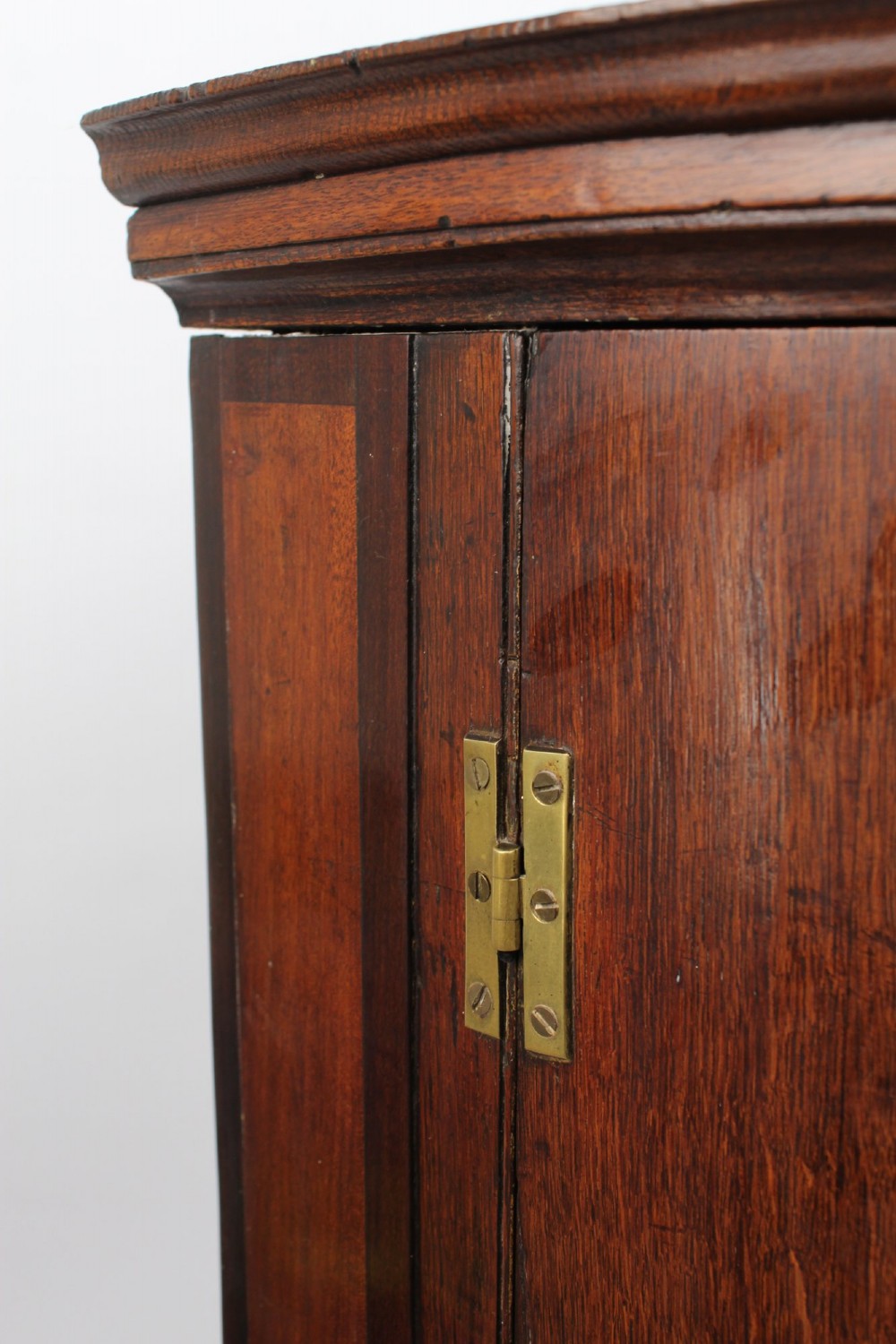 A Georgian oak bow-front corner cupboard with twin doors, exposed brass H-hinges, crossbanded veneer borders, and central brass escutcheons. View VIII