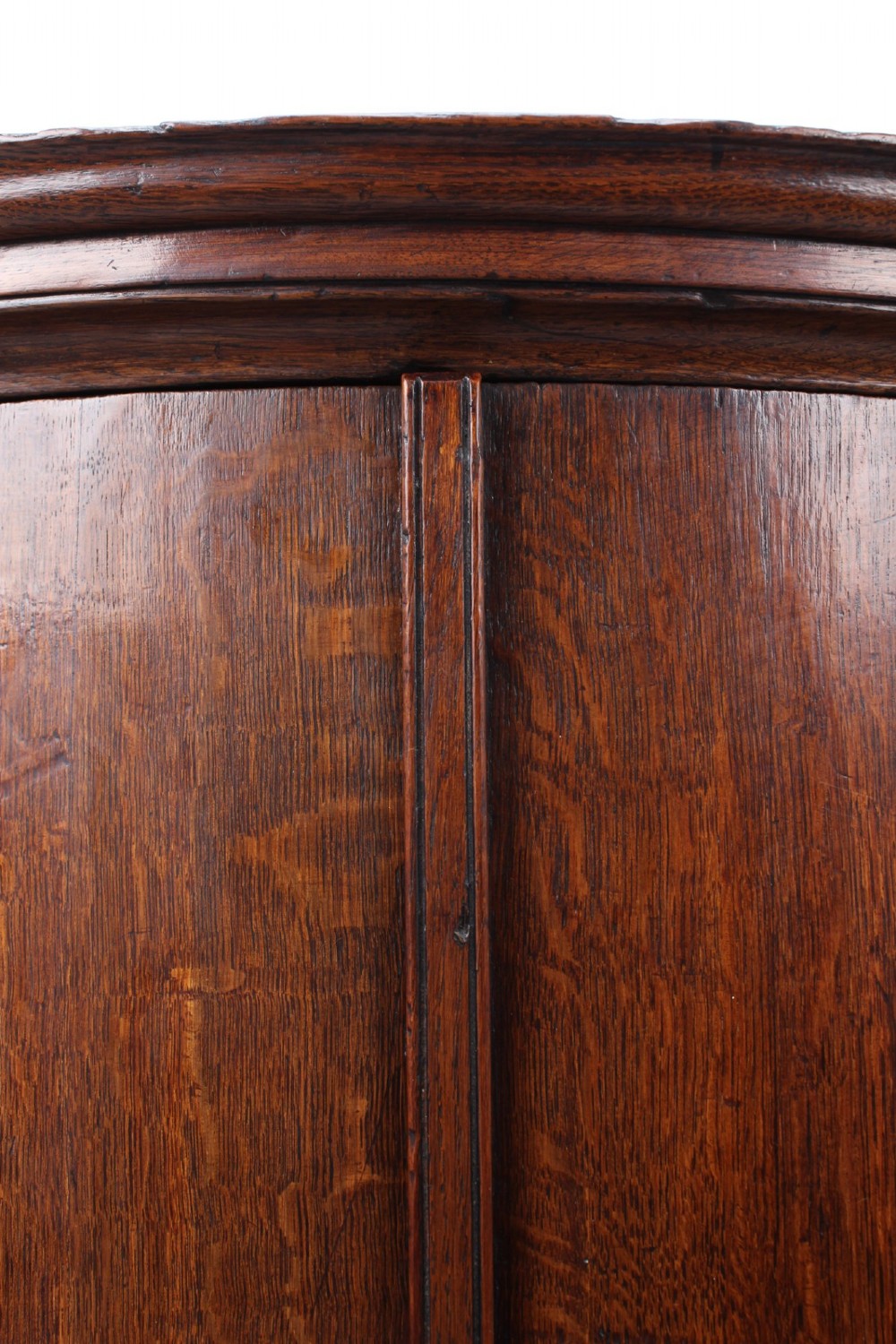 A Georgian oak bow-front corner cupboard with twin doors, exposed brass H-hinges, crossbanded veneer borders, and central brass escutcheons. View IX
