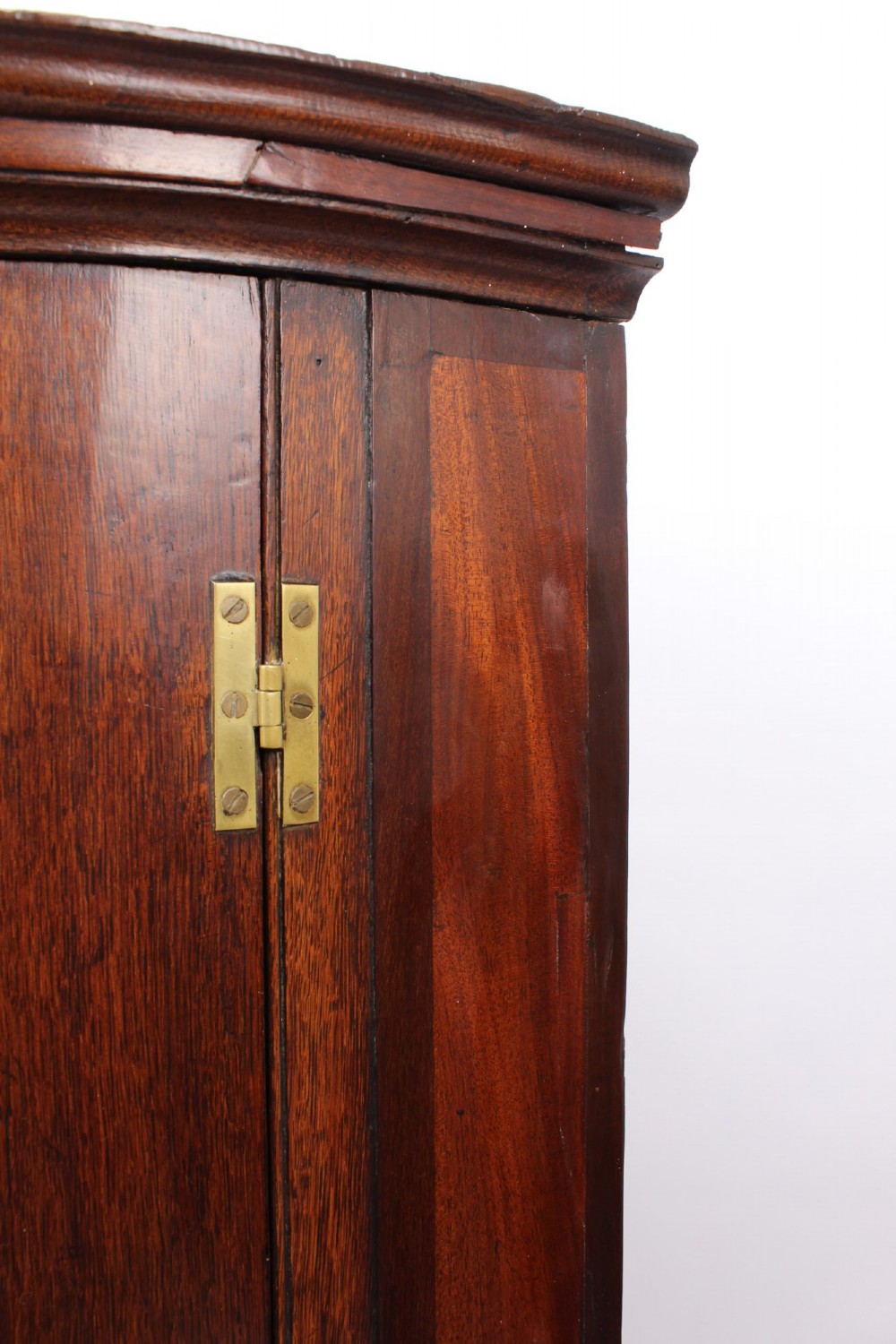 A Georgian oak bow-front corner cupboard with twin doors, exposed brass H-hinges, crossbanded veneer borders, and central brass escutcheons. View X