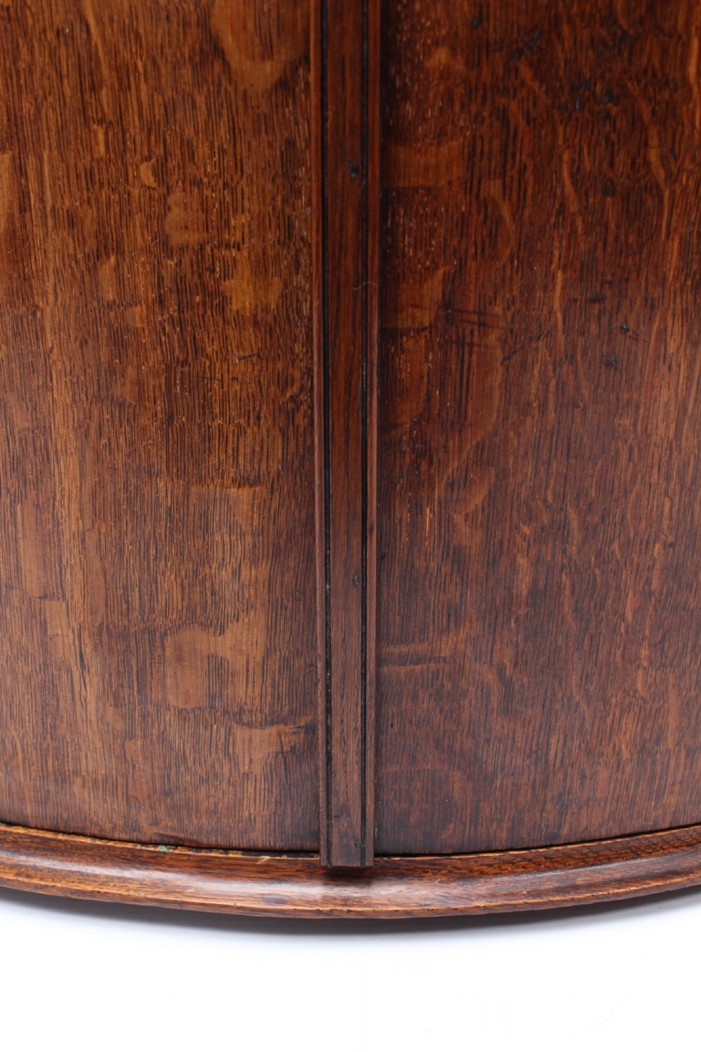 A Georgian oak bow-front corner cupboard with twin doors, exposed brass H-hinges, crossbanded veneer borders, and central brass escutcheons. View XII