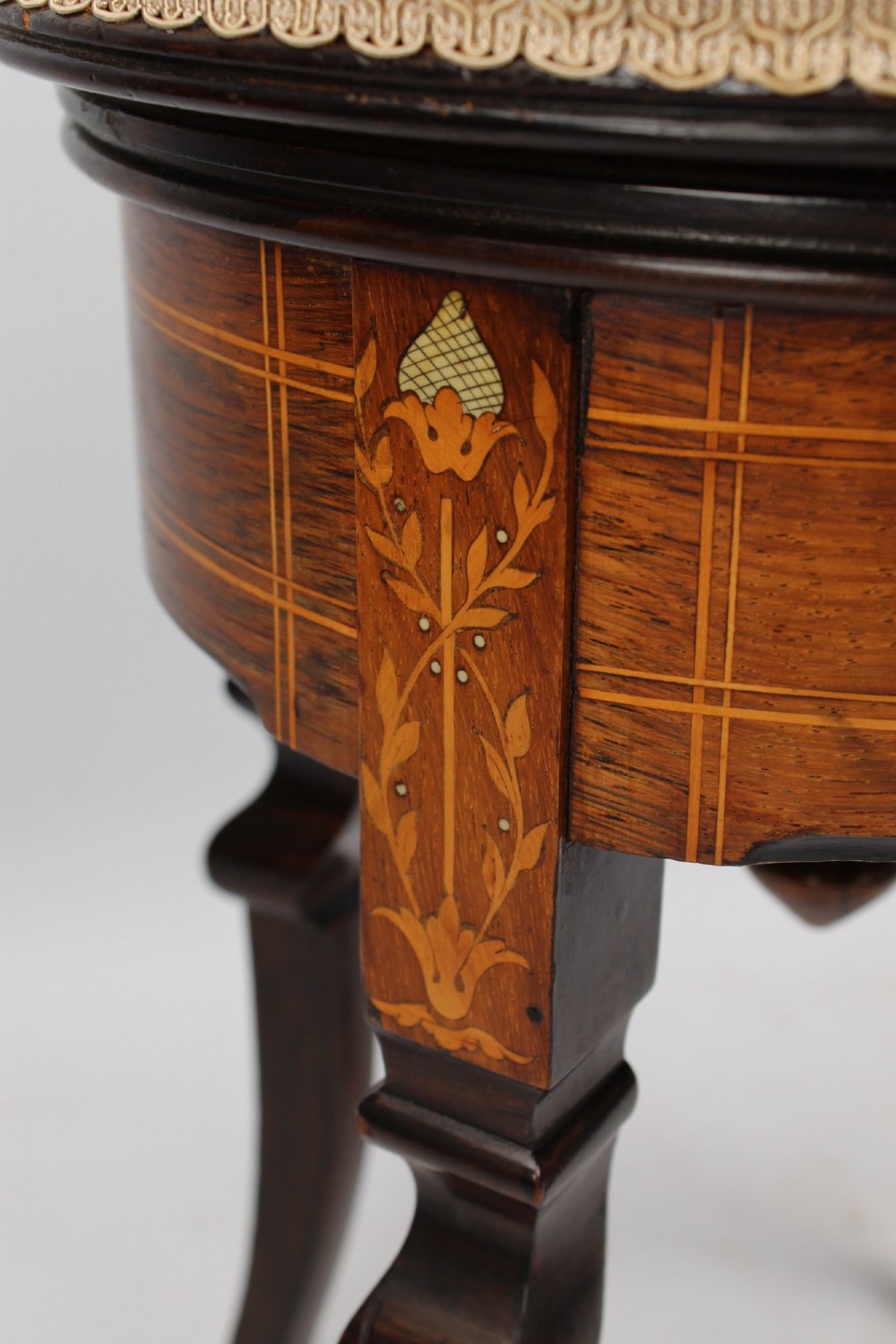 A circular padded beige stool on a dark rosewood base featuring floral marquetry and curved legs. View V