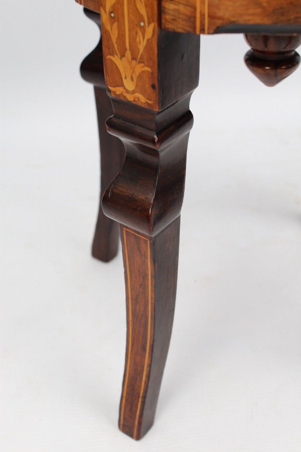 A circular padded beige stool on a dark rosewood base featuring floral marquetry and curved legs. View VI