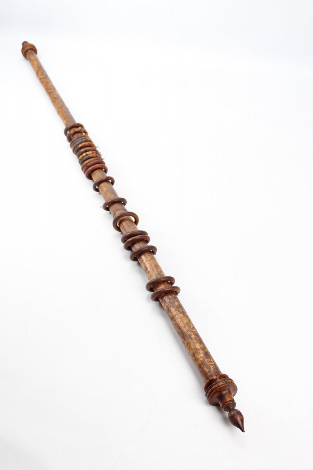 A long natural bamboo curtain pole featuring turned wooden finials at both ends and a set of matching wooden curtain rings stacked near one end. View II
