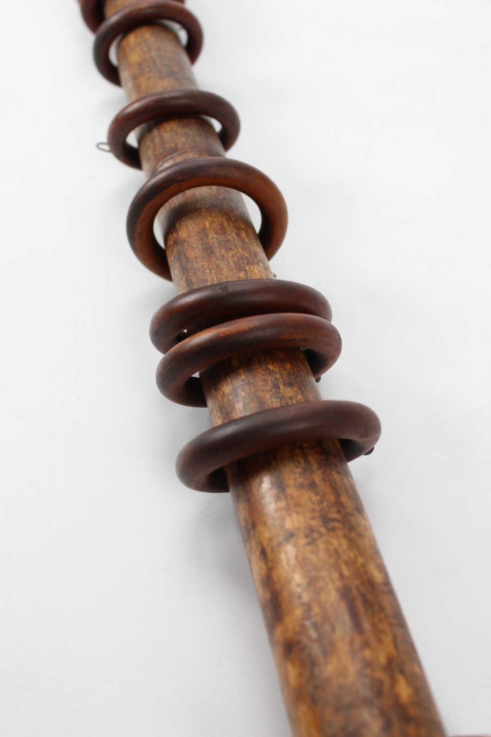 A long natural bamboo curtain pole featuring turned wooden finials at both ends and a set of matching wooden curtain rings stacked near one end. View XII