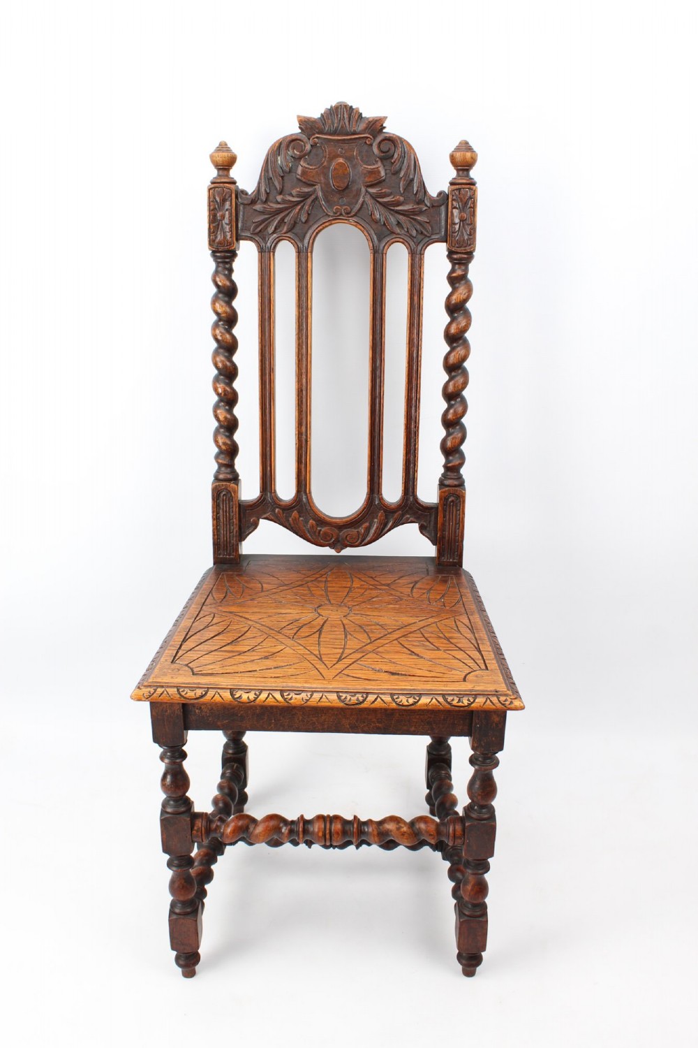 A set of four Victorian Gothic Revival dark oak chairs featuring carved floral crestings, barley twist supports, and carved geometric patterned wooden seats. View III