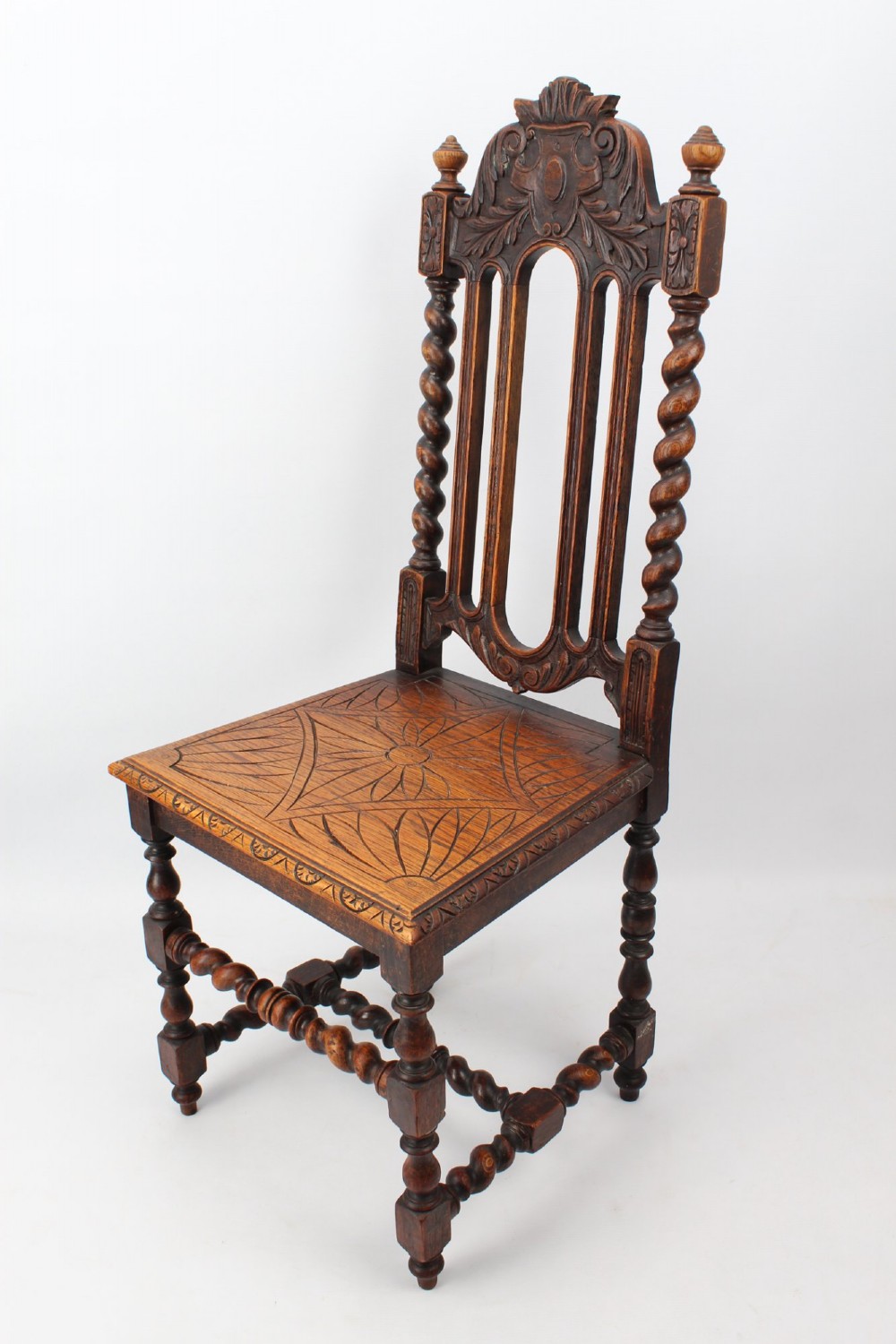 A set of four Victorian Gothic Revival dark oak chairs featuring carved floral crestings, barley twist supports, and carved geometric patterned wooden seats. View IV