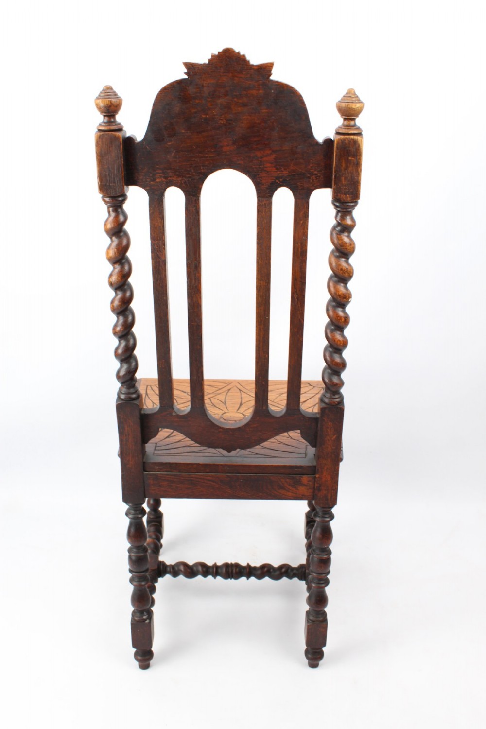 A set of four Victorian Gothic Revival dark oak chairs featuring carved floral crestings, barley twist supports, and carved geometric patterned wooden seats. View VI