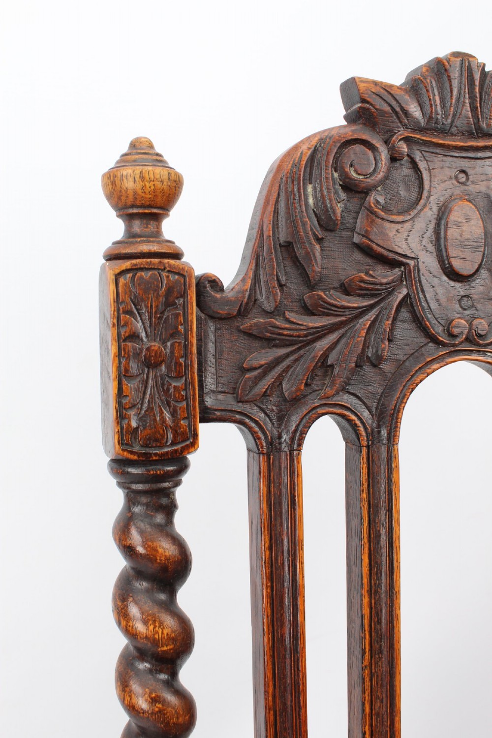 A set of four Victorian Gothic Revival dark oak chairs featuring carved floral crestings, barley twist supports, and carved geometric patterned wooden seats. View XI