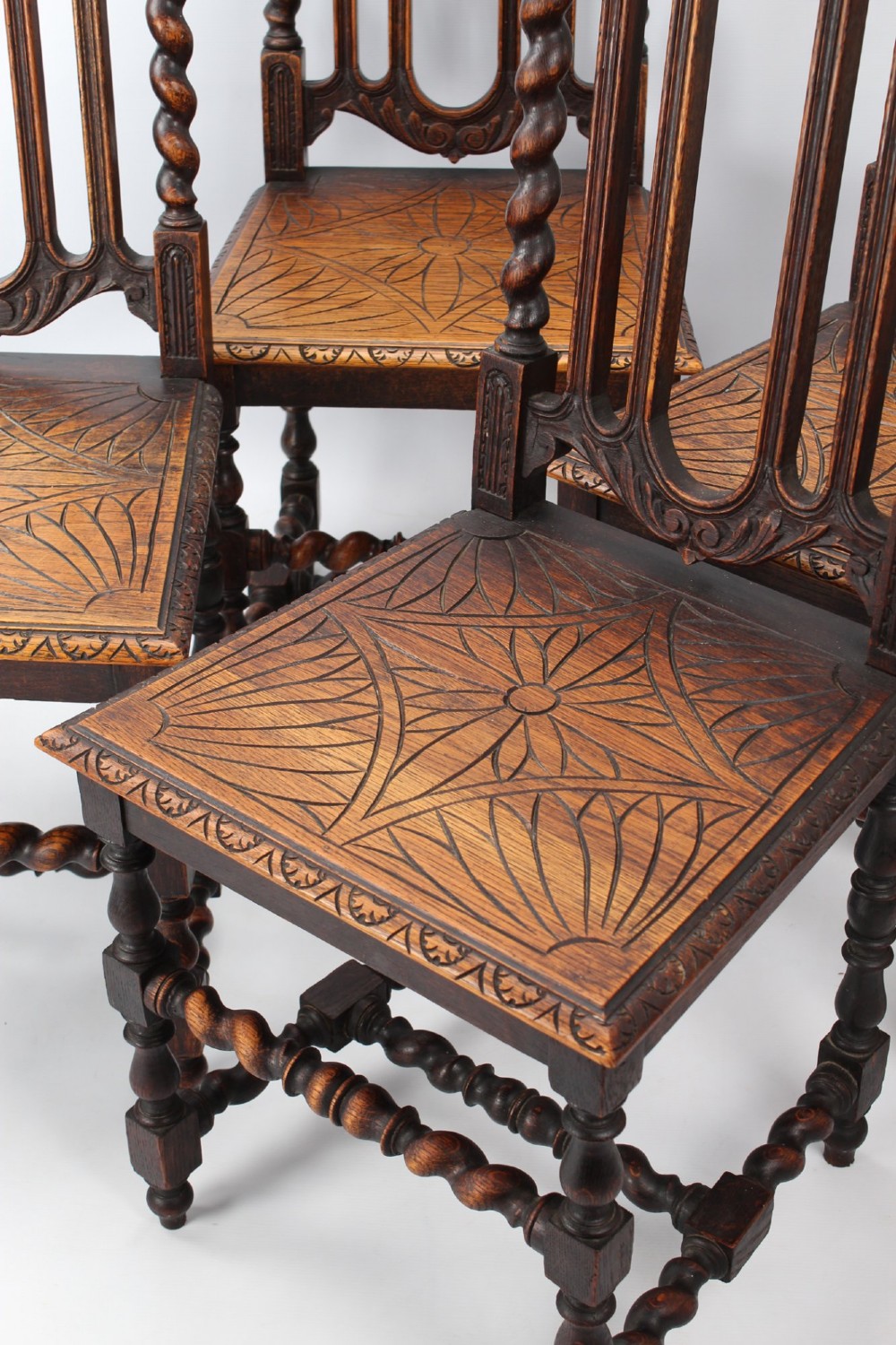A set of four Victorian Gothic Revival dark oak chairs featuring carved floral crestings, barley twist supports, and carved geometric patterned wooden seats. View XIII