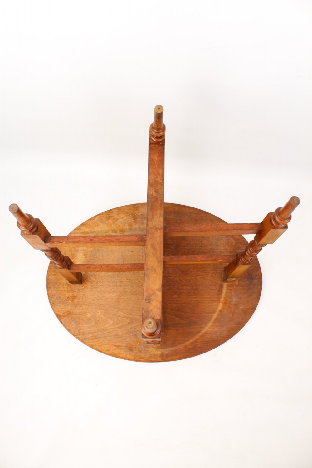 A Victorian burr walnut oval table shown with its top tilted vertically on a wooden frame with turned legs. View V