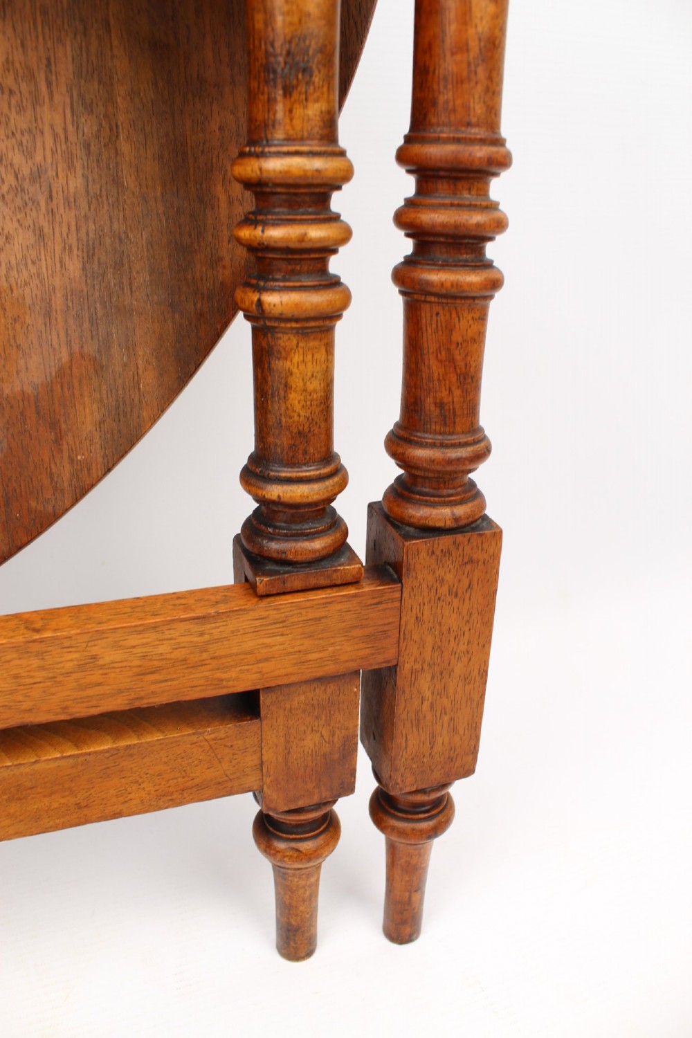 A Victorian burr walnut oval table shown with its top tilted vertically on a wooden frame with turned legs. View VI