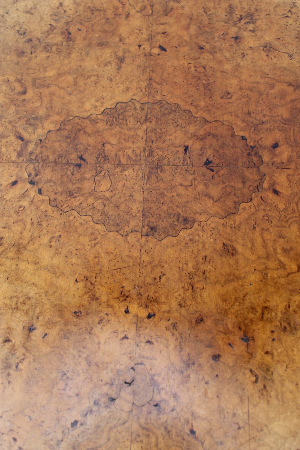 A Victorian burr walnut oval table shown with its top tilted vertically on a wooden frame with turned legs. View VIII