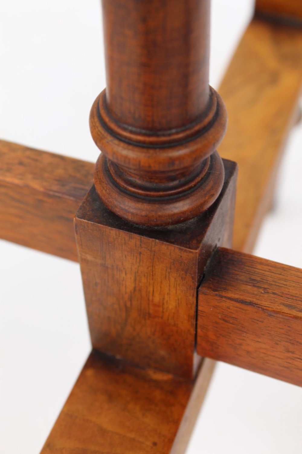 A Victorian burr walnut oval table shown with its top tilted vertically on a wooden frame with turned legs. View X