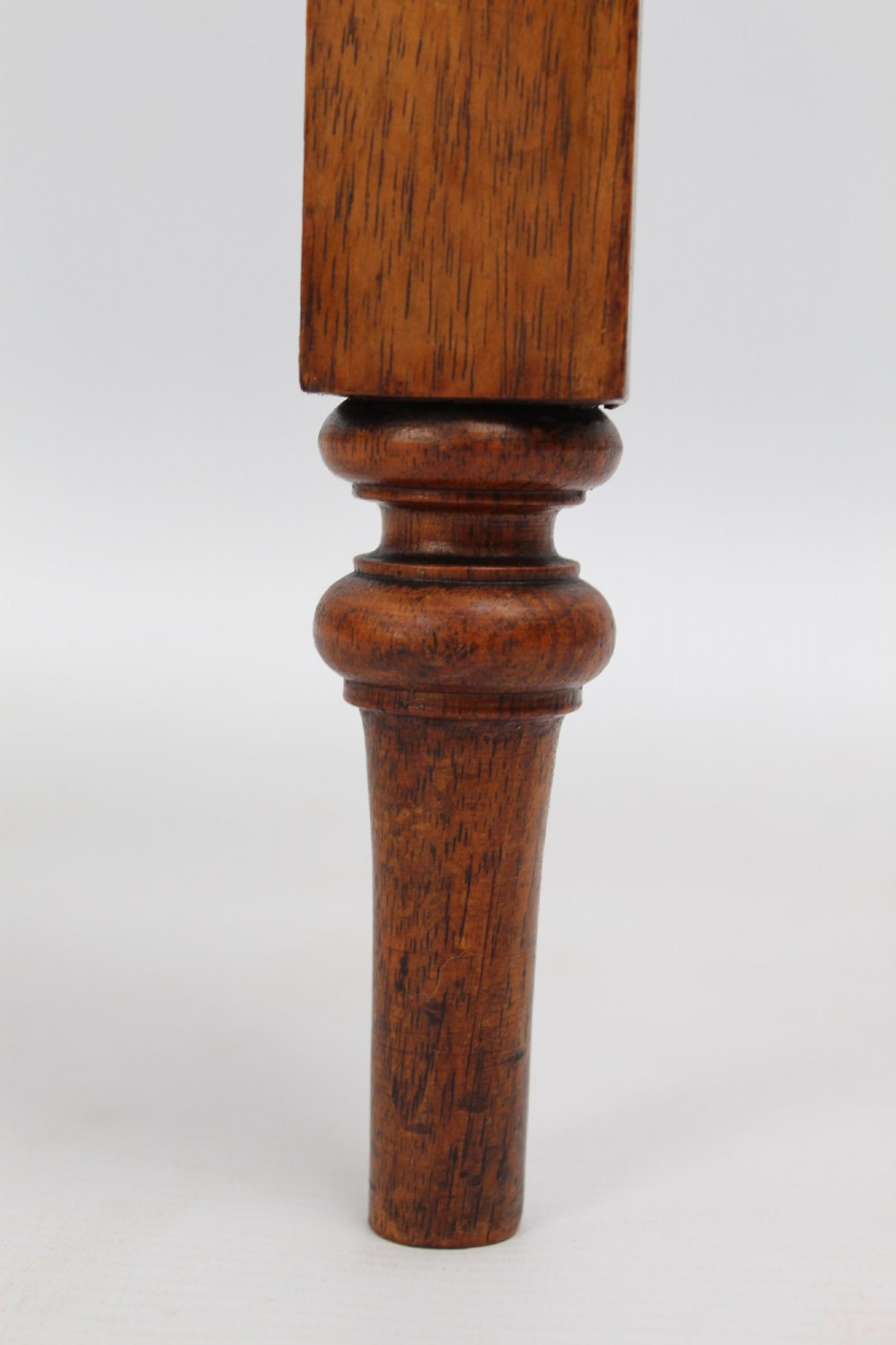 A Victorian burr walnut oval table shown with its top tilted vertically on a wooden frame with turned legs. View XI