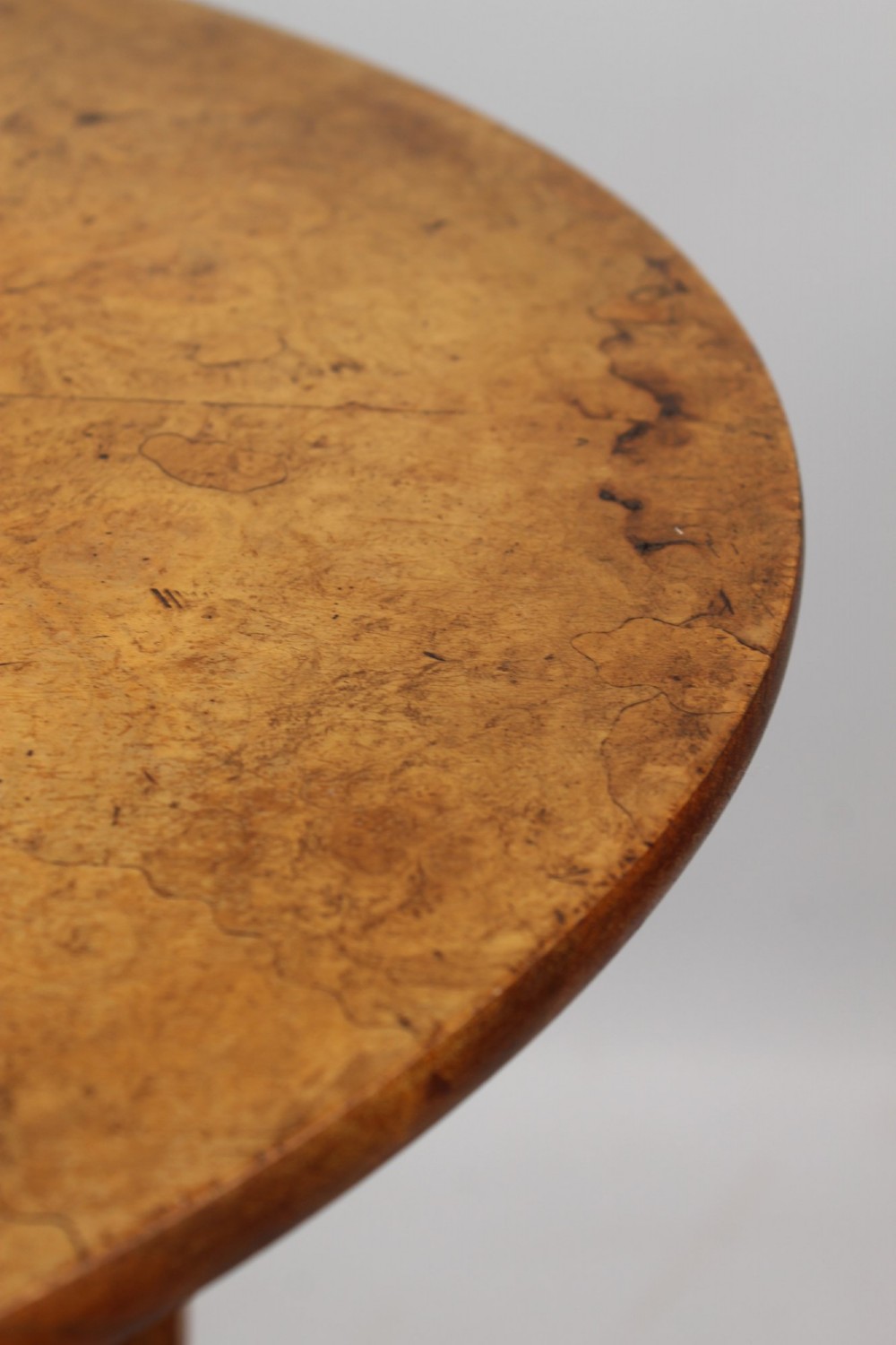 A Victorian burr walnut oval table shown with its top tilted vertically on a wooden frame with turned legs. View XII