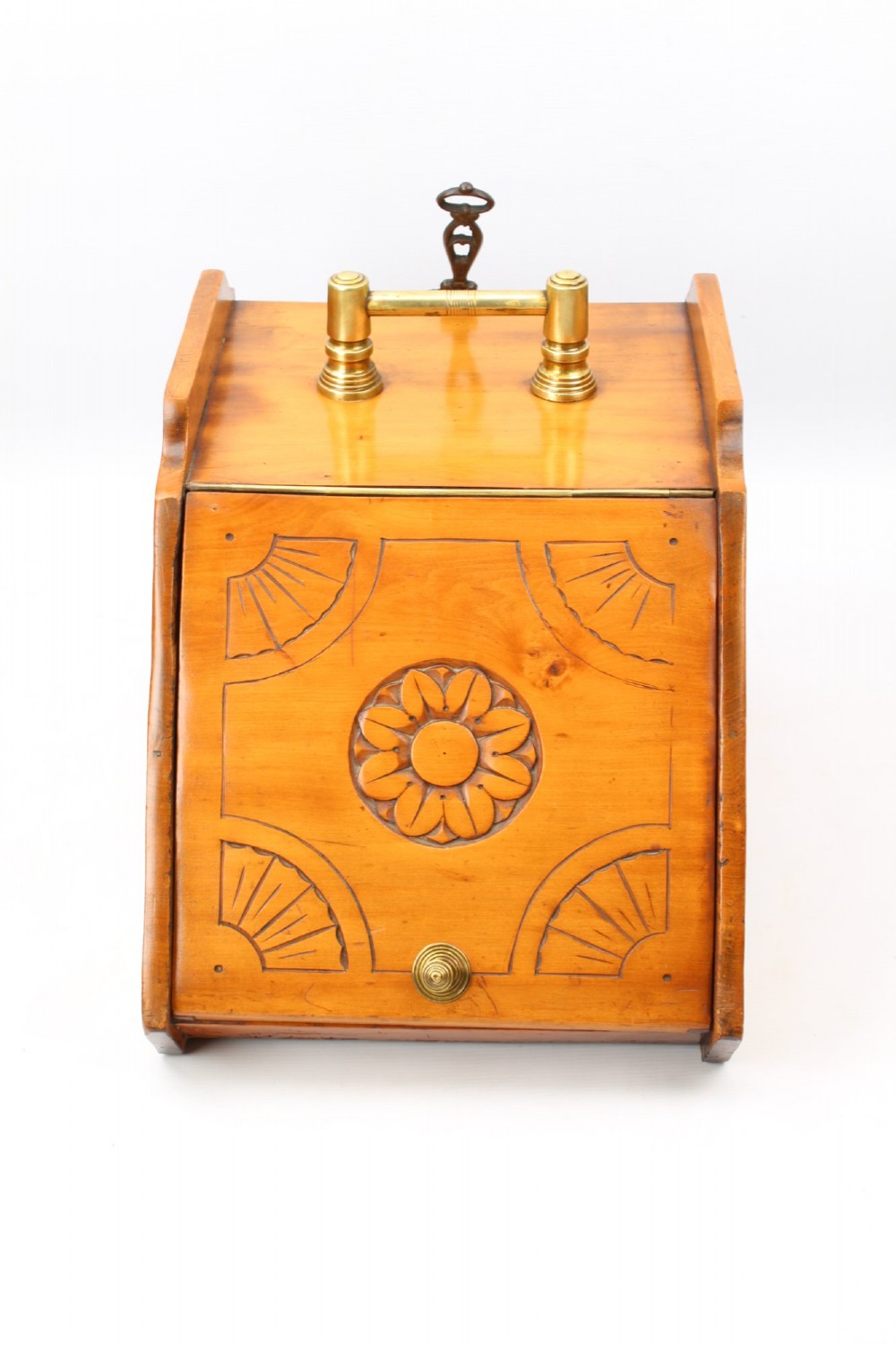 A slant-front Victorian wooden coal scuttle featuring carved floral motifs, a brass top handle, and a metal shovel stowed at the back. View II