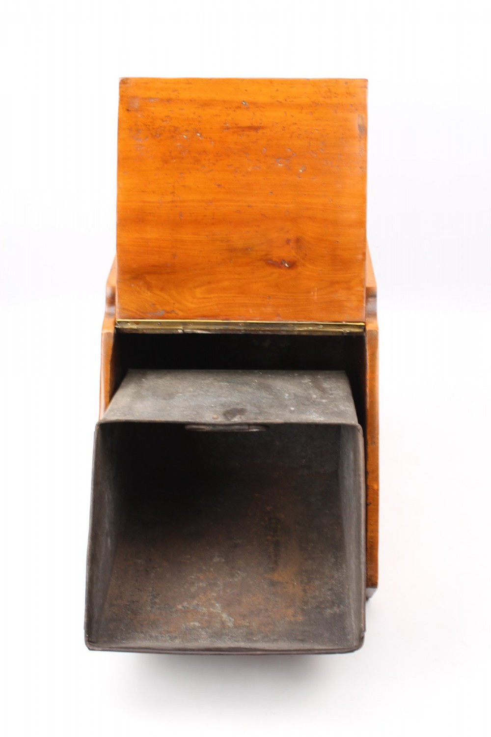 A slant-front Victorian wooden coal scuttle featuring carved floral motifs, a brass top handle, and a metal shovel stowed at the back. View IV