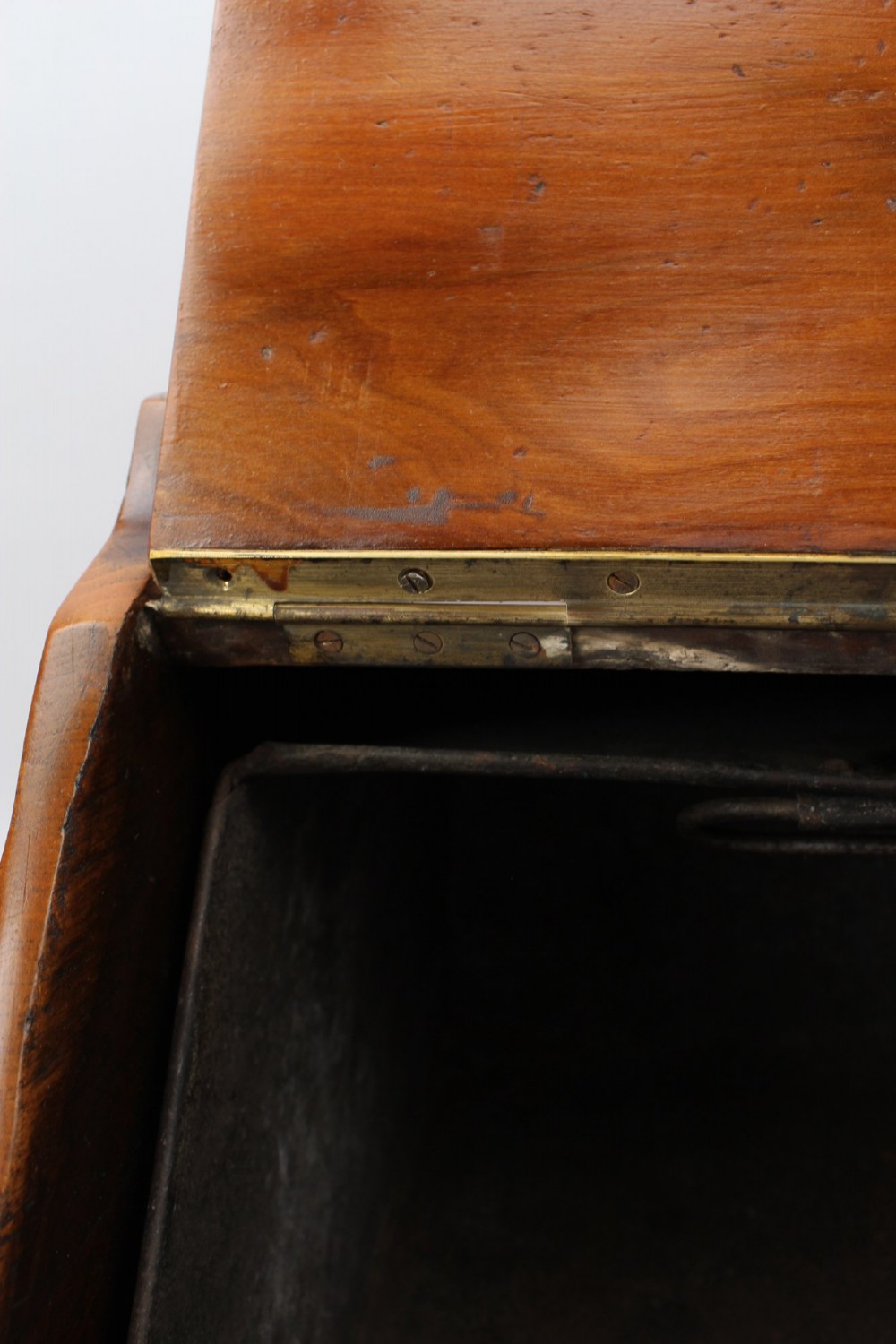 A slant-front Victorian wooden coal scuttle featuring carved floral motifs, a brass top handle, and a metal shovel stowed at the back. View XII