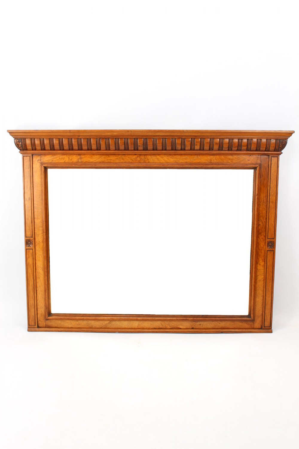 A large rectangular Victorian oak overmantel mirror featuring a moulded frame with a fluted frieze top cornice and carved side rosettes.