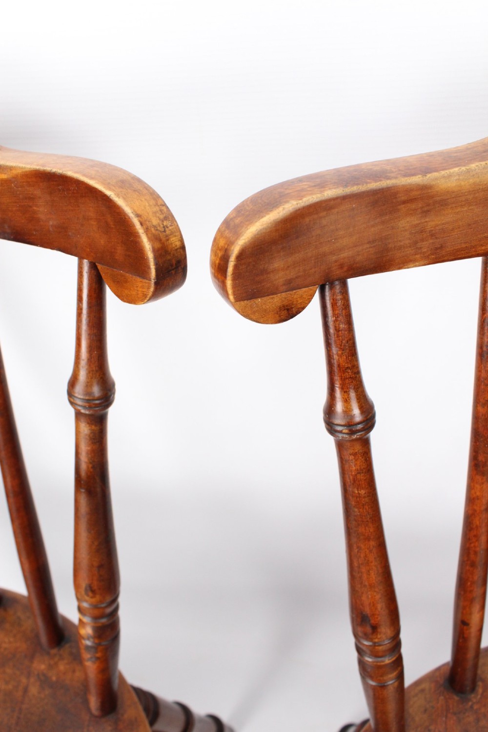 A pair of warm brown wooden kitchen chairs featuring spindle backs, turned legs, and solid timber seats. View X