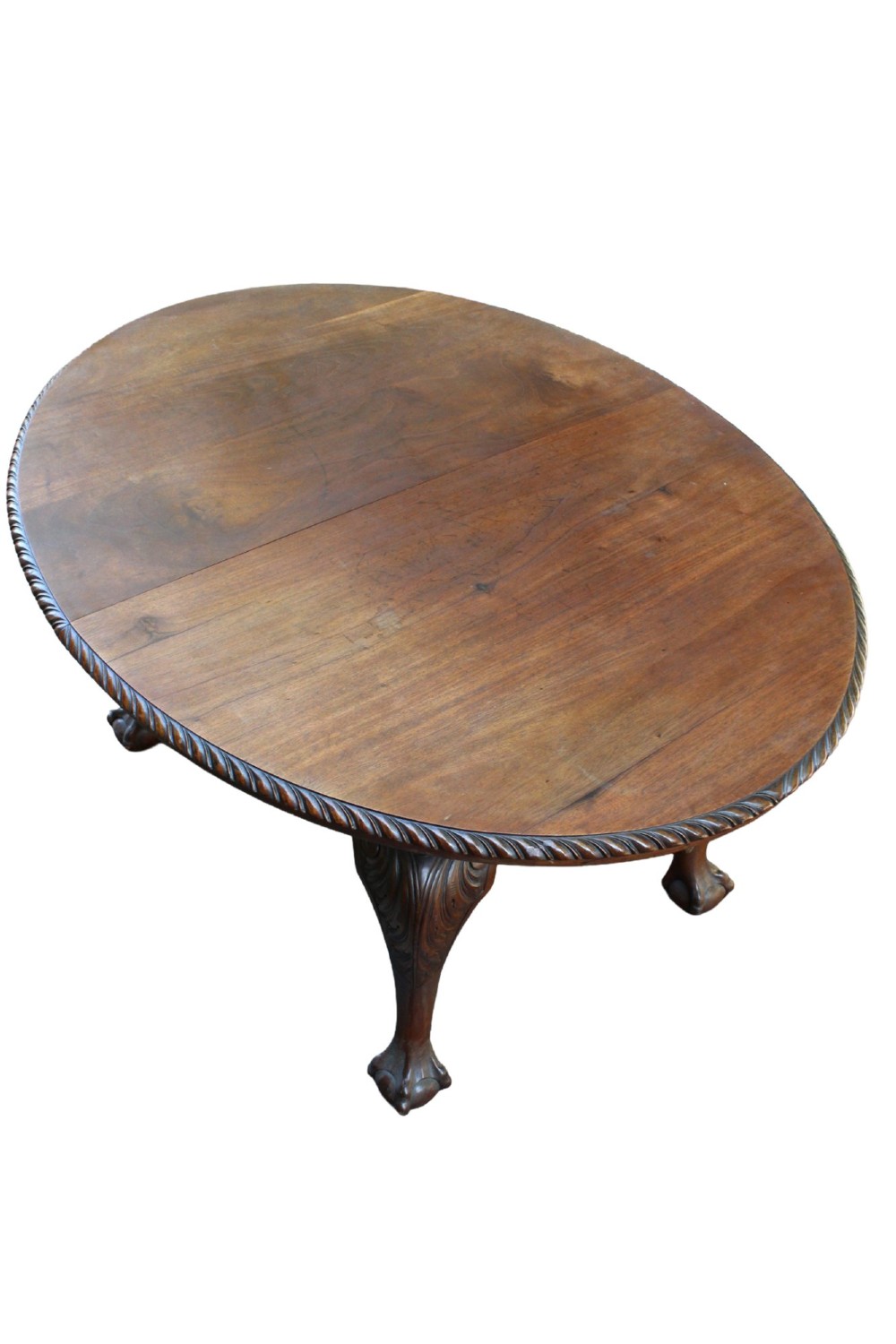 An antique Edwardian extending mahogany dining table featuring an oval top with gadrooned edges and carved cabriole legs terminating in ball-and-claw feet. View III