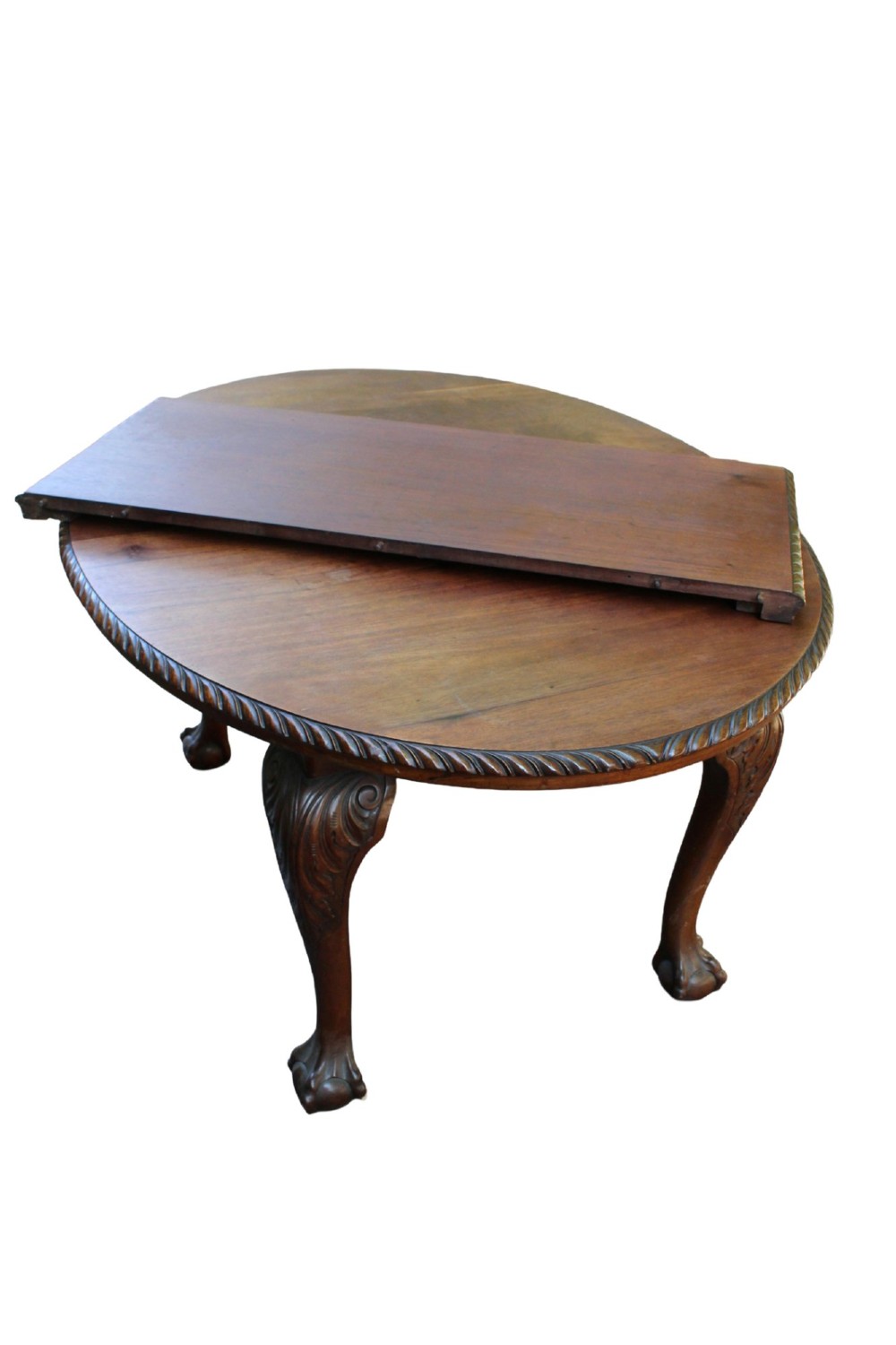 An antique Edwardian extending mahogany dining table featuring an oval top with gadrooned edges and carved cabriole legs terminating in ball-and-claw feet. View IV