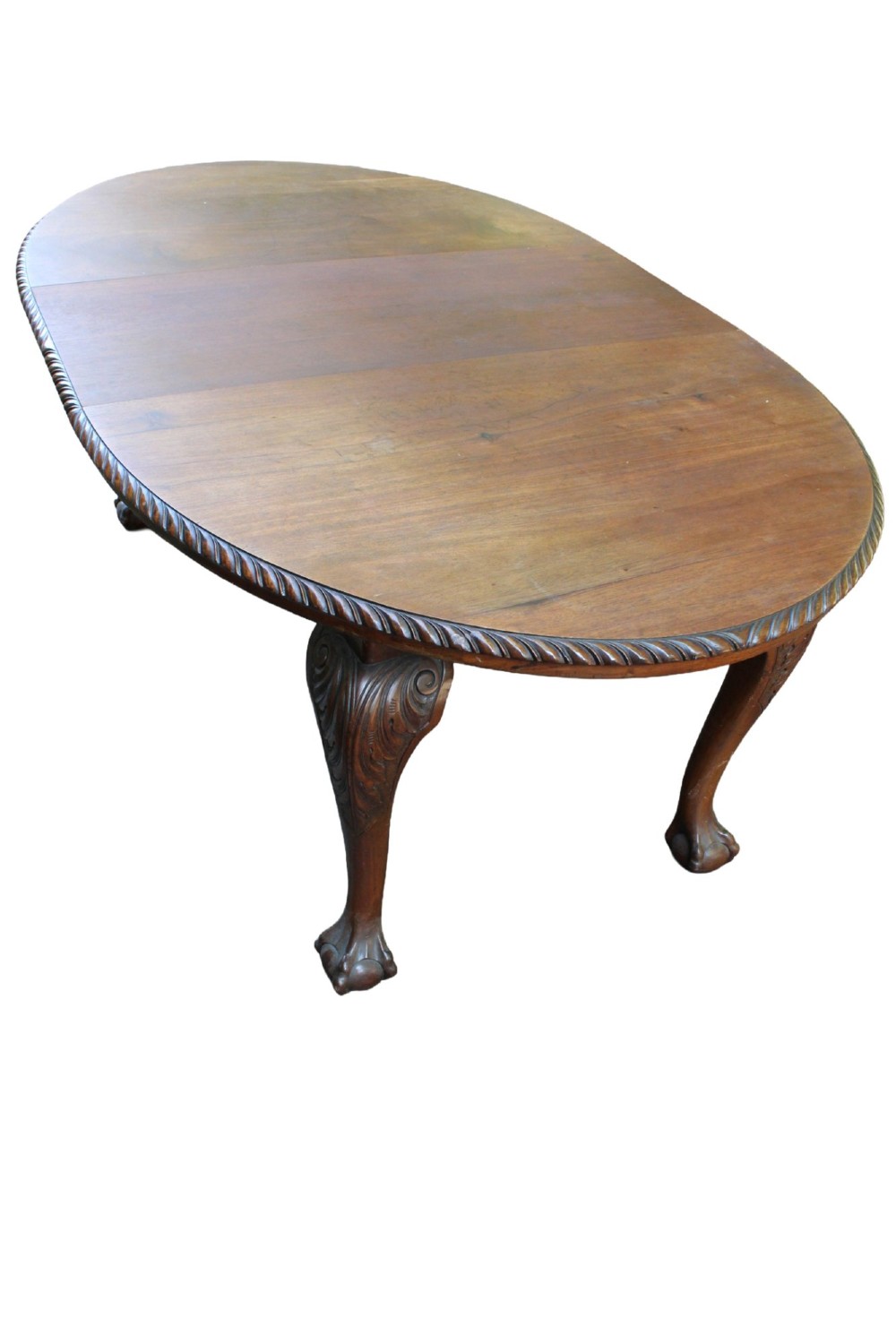 An antique Edwardian extending mahogany dining table featuring an oval top with gadrooned edges and carved cabriole legs terminating in ball-and-claw feet. View VI