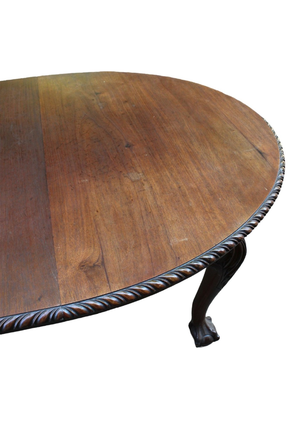 An antique Edwardian extending mahogany dining table featuring an oval top with gadrooned edges and carved cabriole legs terminating in ball-and-claw feet. View XIII