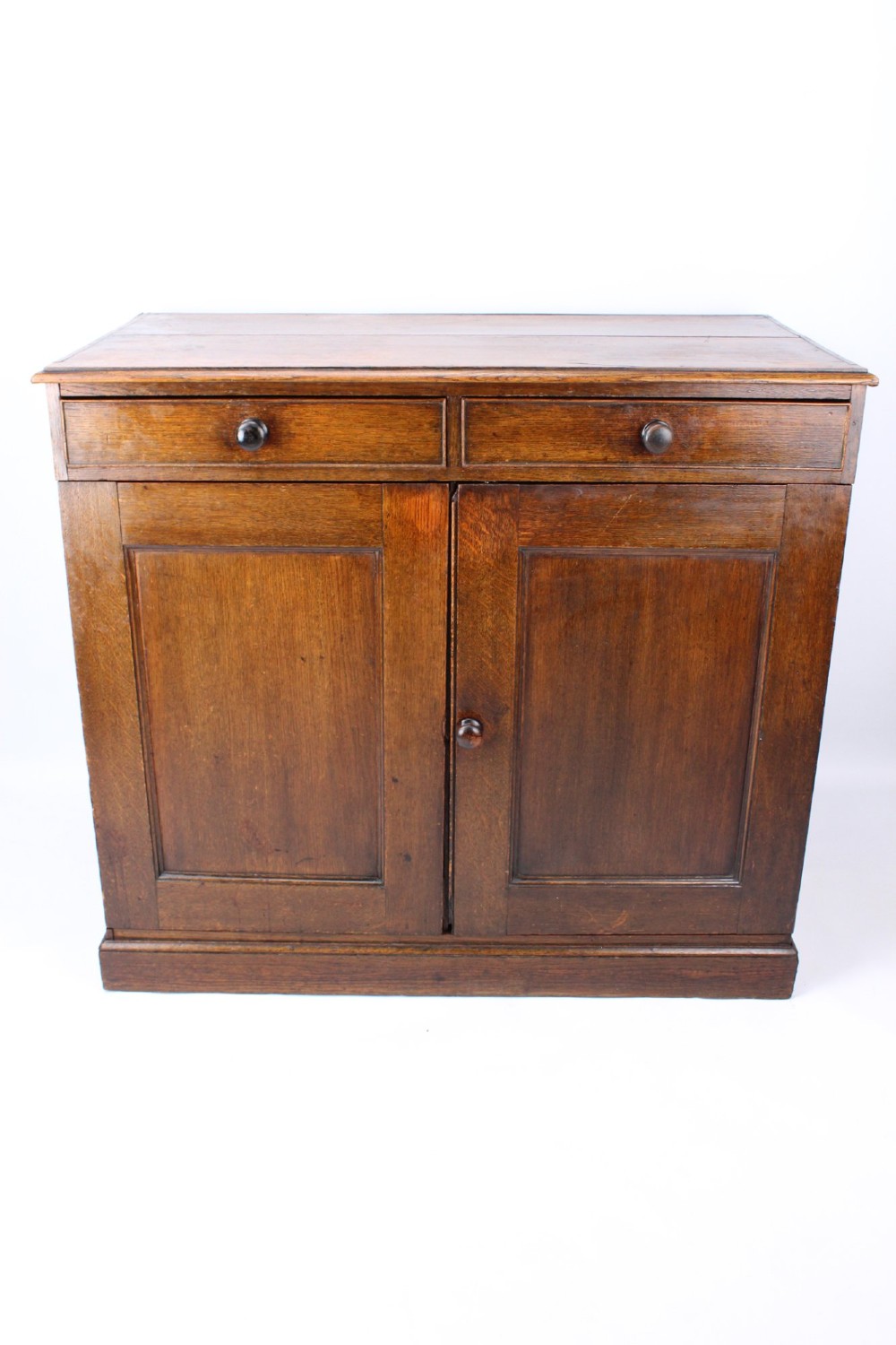A low Georgian oak cupboard featuring two frieze drawers with turned wooden knobs above a pair of panelled cupboard doors.
