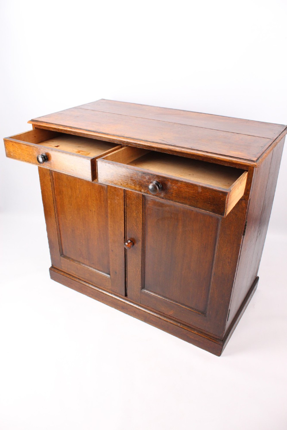 A low Georgian oak cupboard featuring two frieze drawers with turned wooden knobs above a pair of panelled cupboard doors. View IV