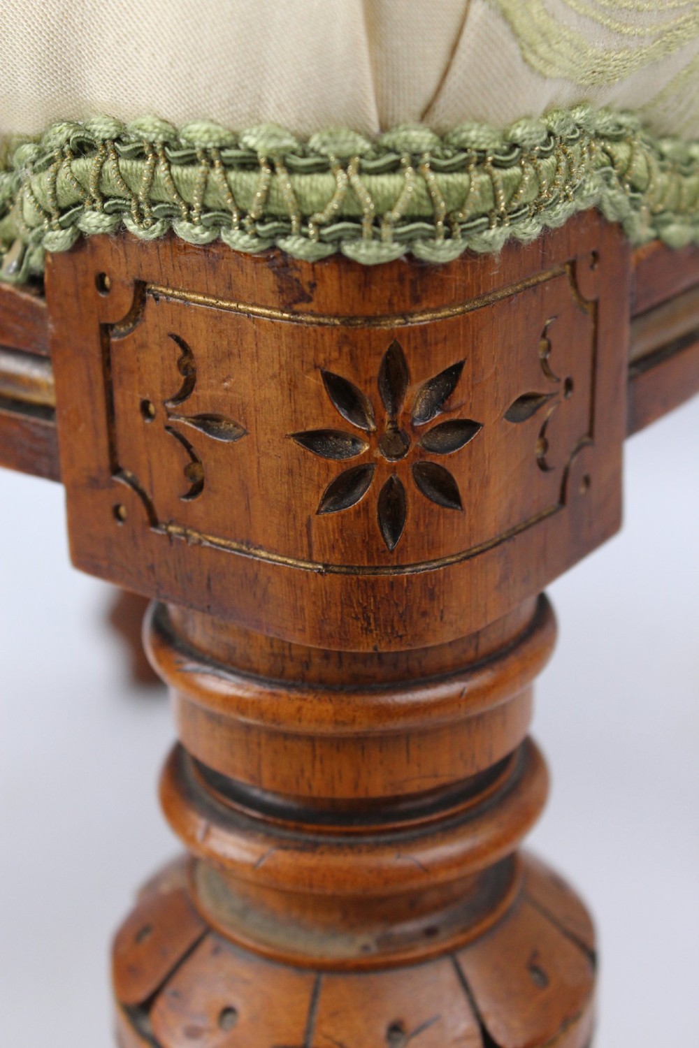 A square Victorian oak dressing stool featuring fluted turned legs with gilt accents and a cream fabric seat decorated with green leaf motifs. View VI