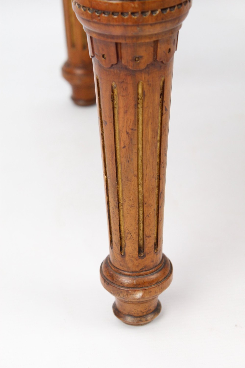A square Victorian oak dressing stool featuring fluted turned legs with gilt accents and a cream fabric seat decorated with green leaf motifs. View VII