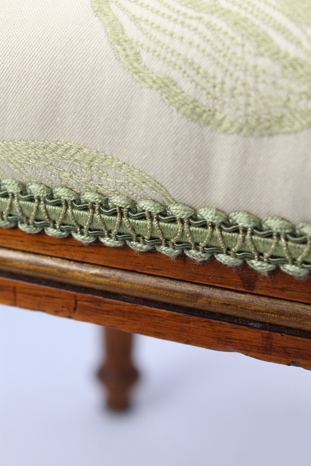 A square Victorian oak dressing stool featuring fluted turned legs with gilt accents and a cream fabric seat decorated with green leaf motifs. View IX