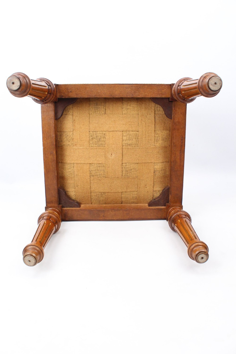 A square Victorian oak dressing stool featuring fluted turned legs with gilt accents and a cream fabric seat decorated with green leaf motifs. View XII