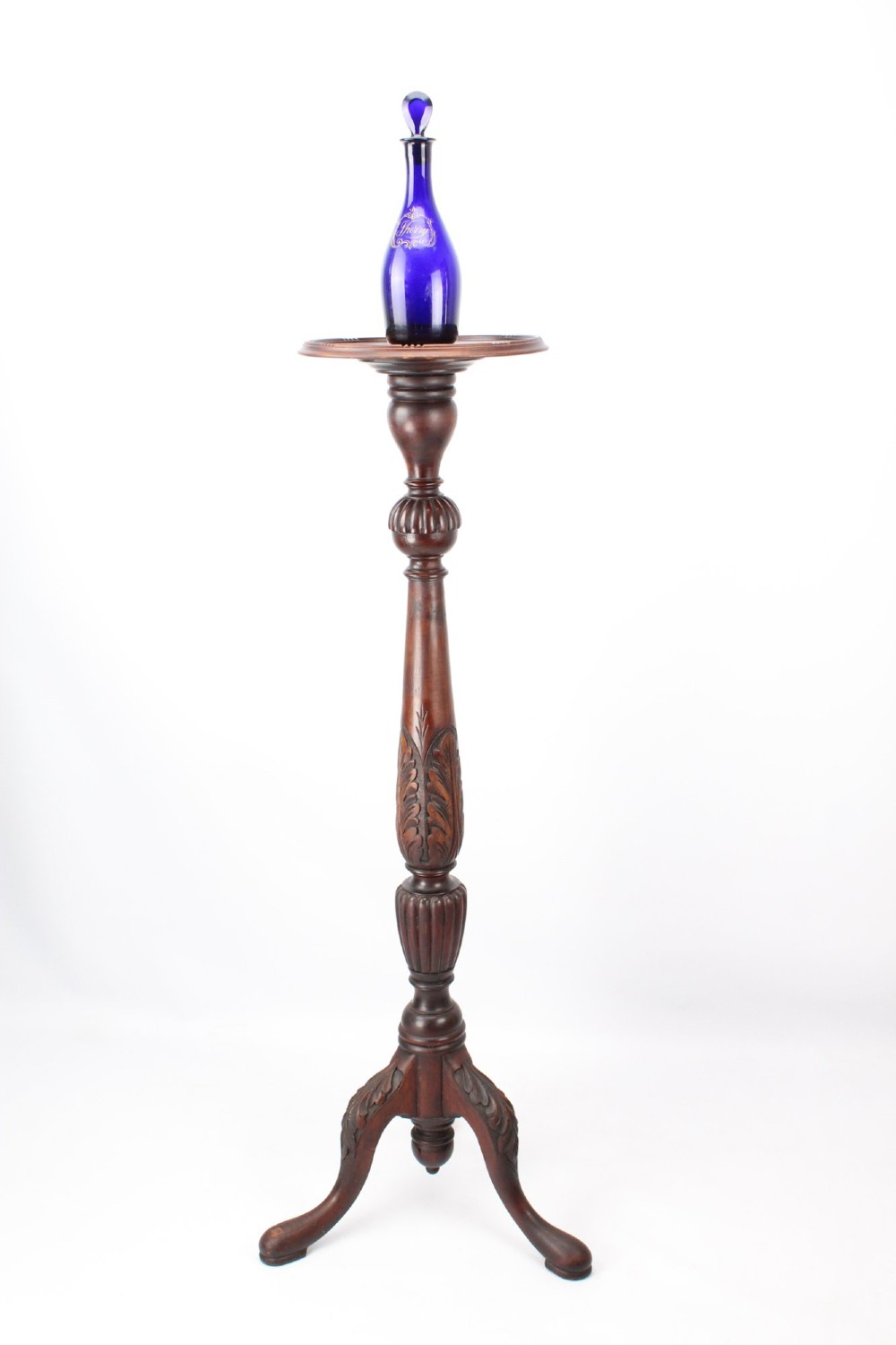 A tall Edwardian mahogany plant stand with a circular top, carved acanthus leaf column, and a tripod base. View II