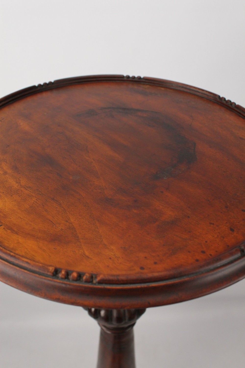 A tall Edwardian mahogany plant stand with a circular top, carved acanthus leaf column, and a tripod base. View V